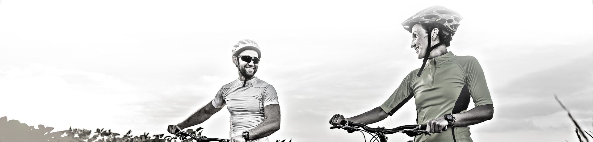 A man and woman walk while holding bikes.