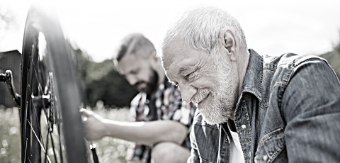 Two men, one elderly and one middle aged, repair a bike.