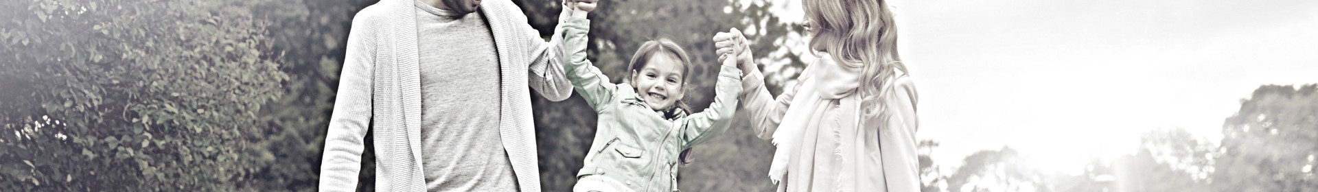 A father and mother play with their daughter by holding her hands.